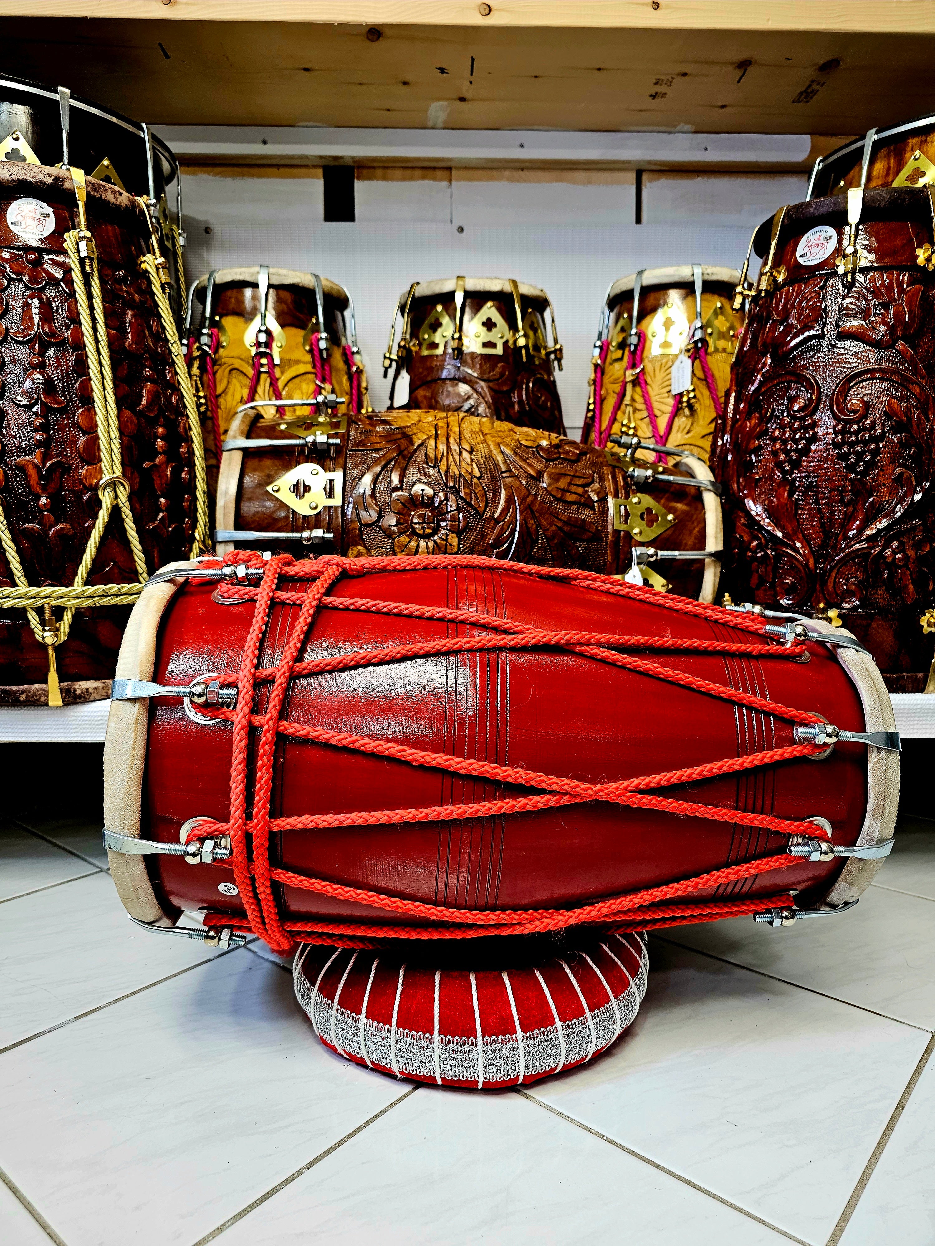 The Ruby Rhythms Pro Dholak - A Red Professional Mango Wood Dholak with Red Ropes Design and Chrome Bolts!