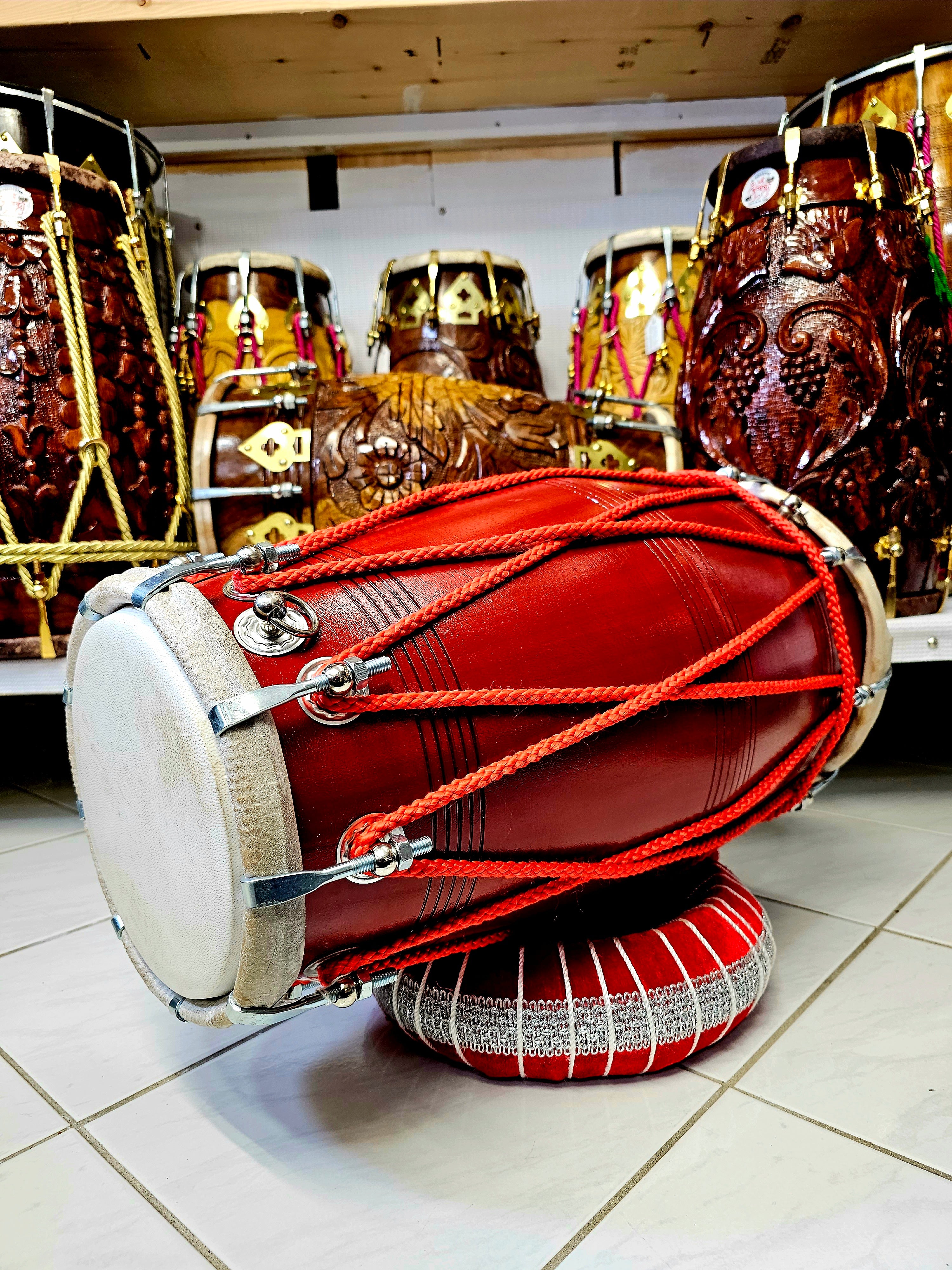 The Ruby Rhythms Pro Dholak - A Red Professional Mango Wood Dholak with Red Ropes Design and Chrome Bolts!