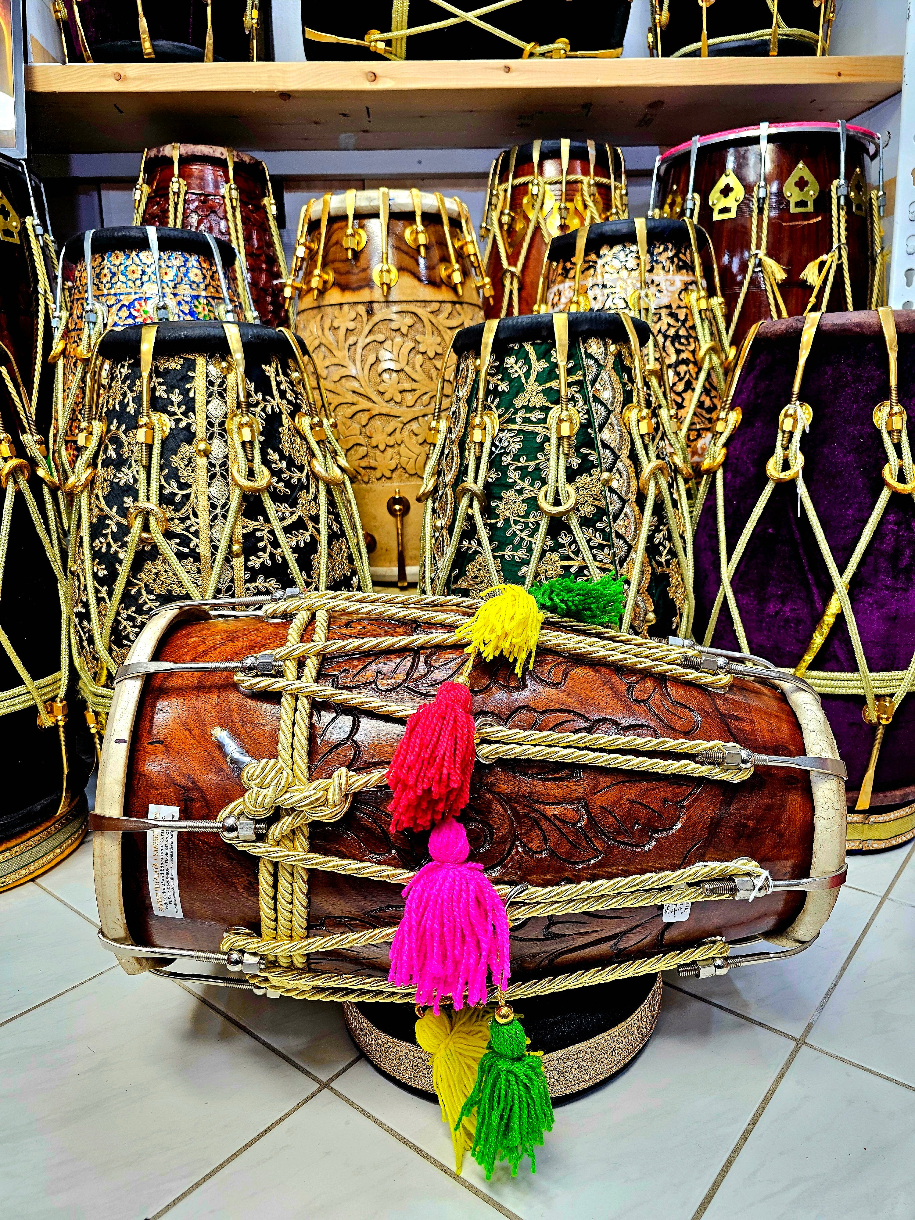 Regal Resonance: Encarved Red Sheesham Dholak with Chrome Bolts, Golden Ropes Design, and Multicolored Tassels