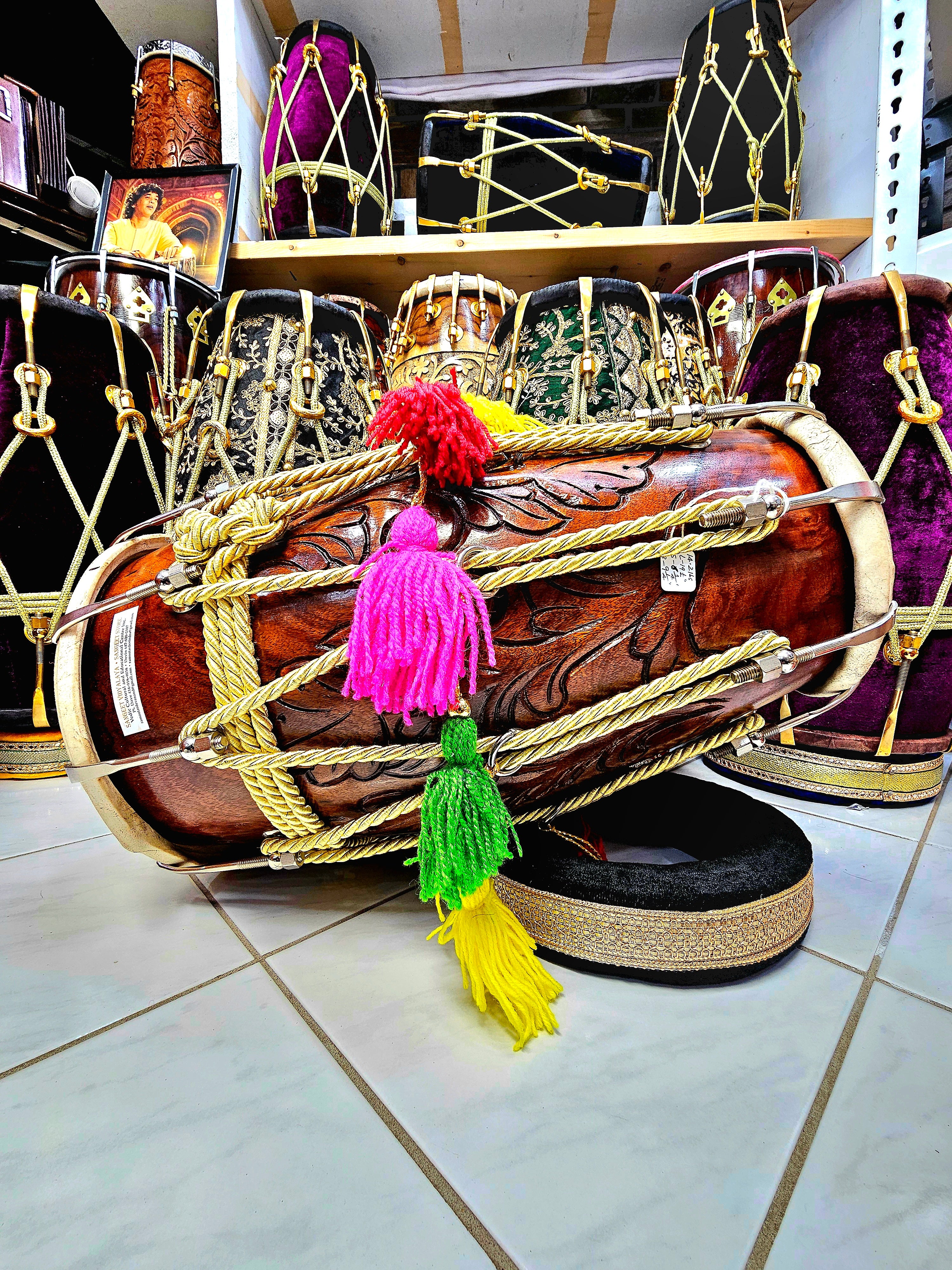 Regal Resonance: Encarved Red Sheesham Dholak with Chrome Bolts, Golden Ropes Design, and Multicolored Tassels