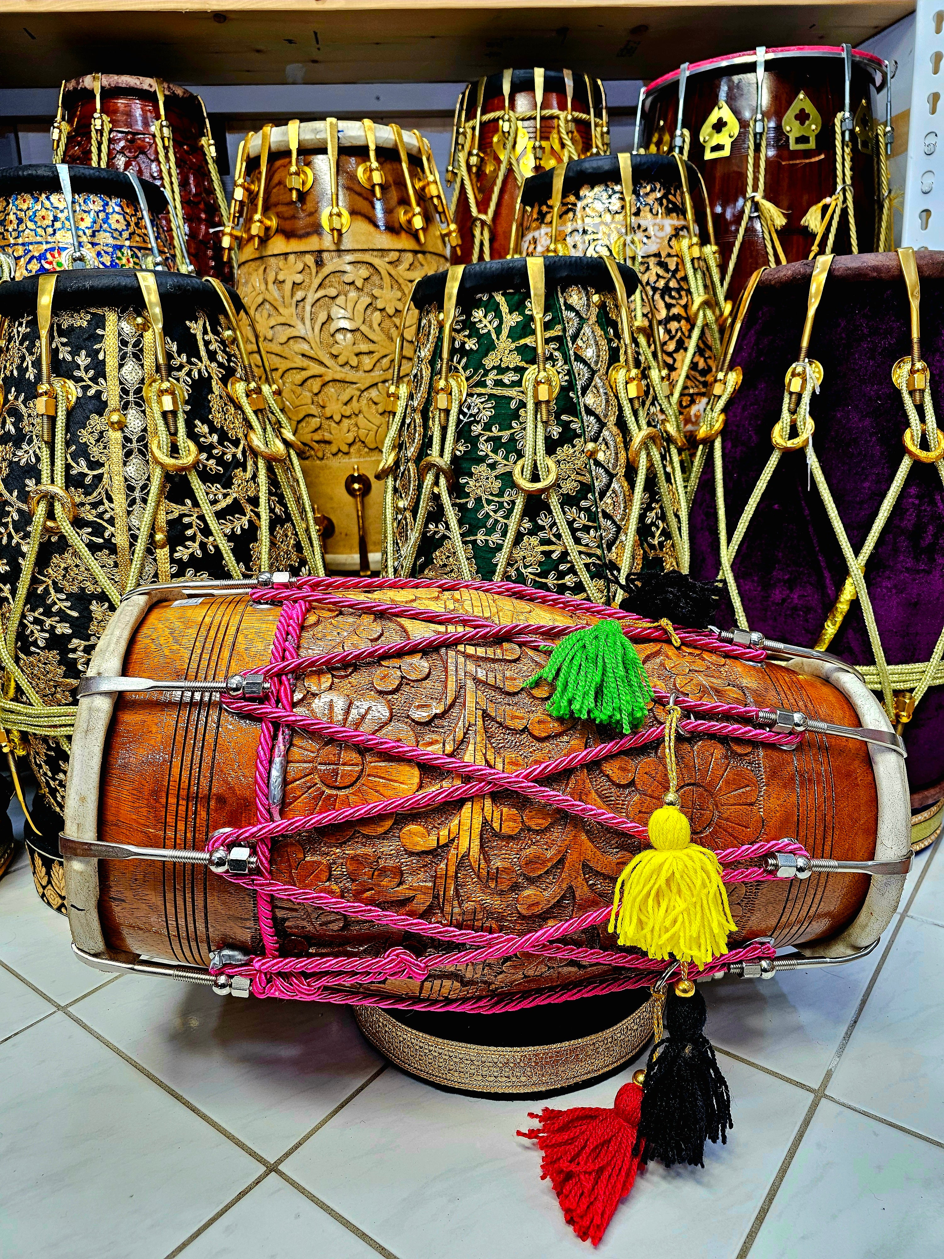 Blossom Melodies: Floral Encarved Red Sheesham Dholak with Chrome Bolts, Pink Roped Design, and Multicolored Tassels